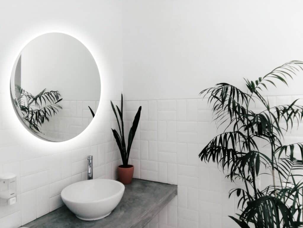 White bathroom with vessel sink and round mirror