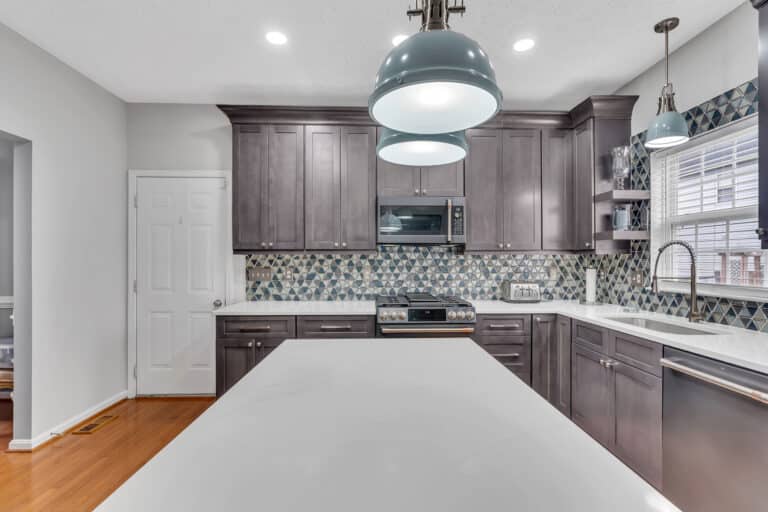 Spacious kitchen project in waldorf md with gray shaker cabinets, white countertop, patterned backsplash, and wood flooring