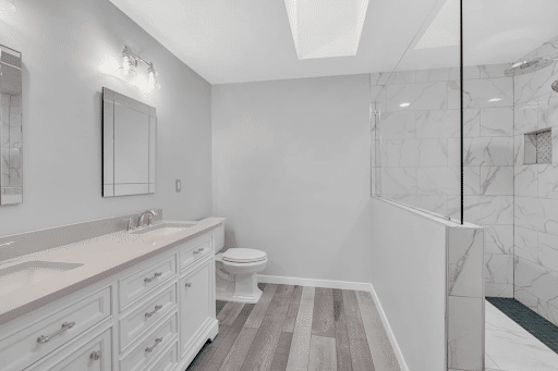 Spacious white bathroom with double-sink vanity, toilet, and shower
