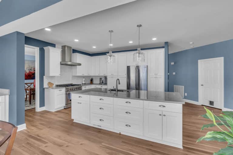 Elegant kitchen with white cabinets, gray countertop and wood flooring