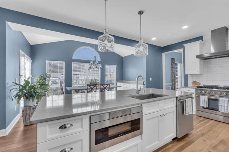 Elegant kitchen with white cabinets, gray countertop and wood flooring