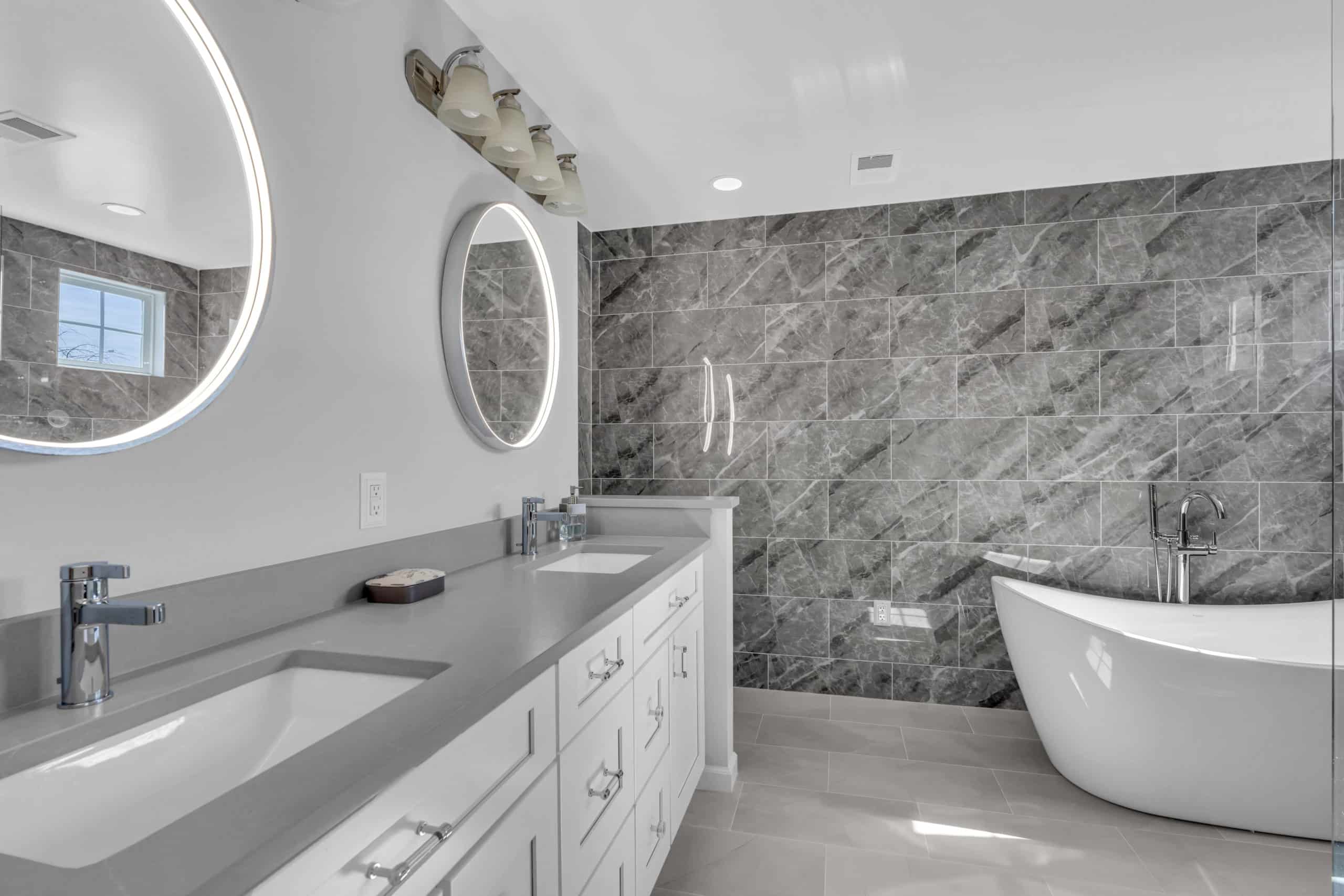 bathroom design with white cabinets, gray countertop, and tub