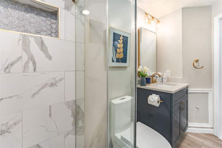 Bathroom with navy blue vanity, with walk-in shower, and toilet