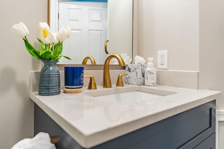 Navy blue vanity, with white countertop and gold faucet