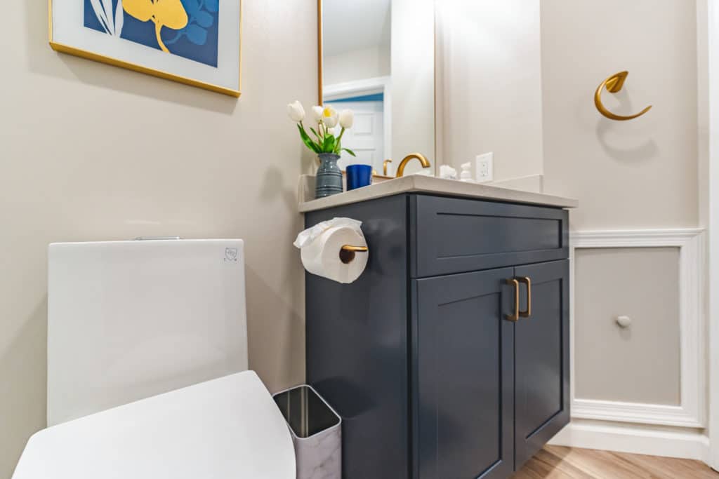 Bathroom with navy blue vanity, and toilet