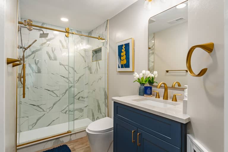 Bathroom with navy blue vanity, with walk-in shower, and toilet