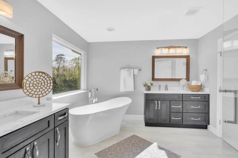 Elegant bathroom with 2 separated gray vanities and tub in middle