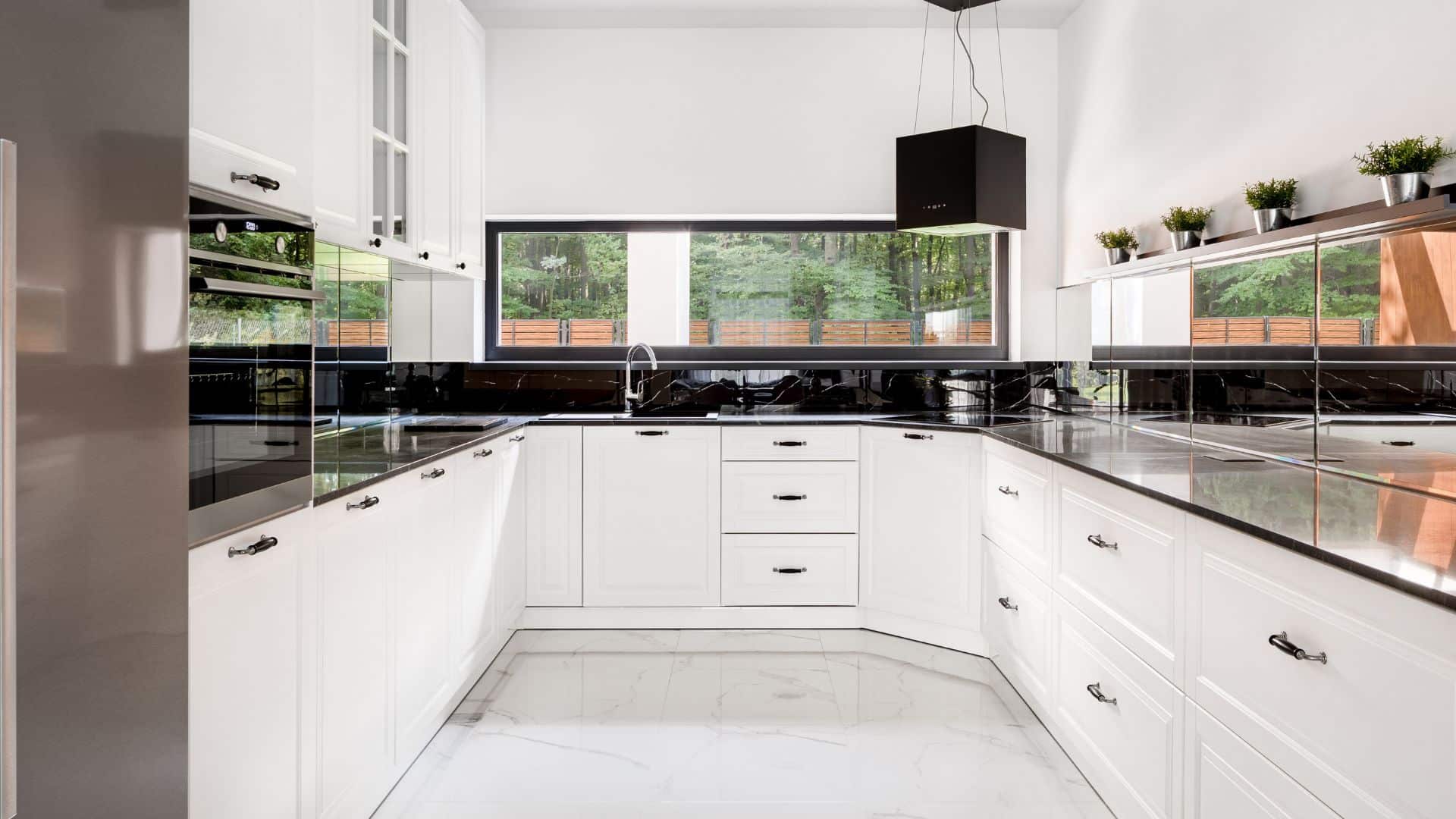U-shaped kitchen with white shaker cabinets and black countertops