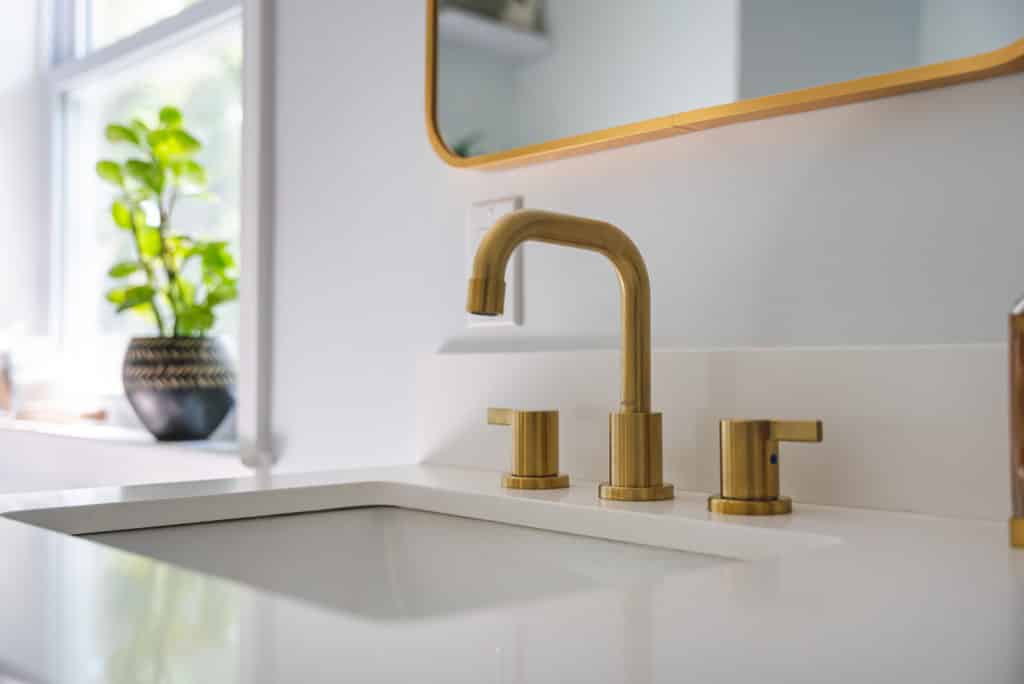 Gold faucet and sink on white countertop