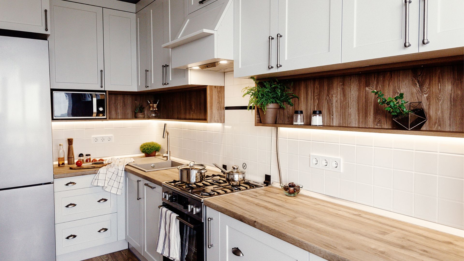 L type kitchen with white shaker cabinets and wood countertops