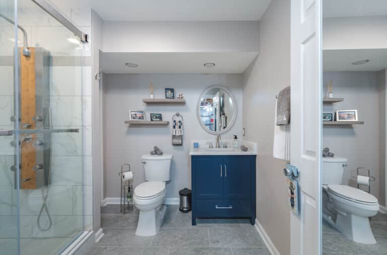 Modern bathroom style with navy vanity, toilet, and shower