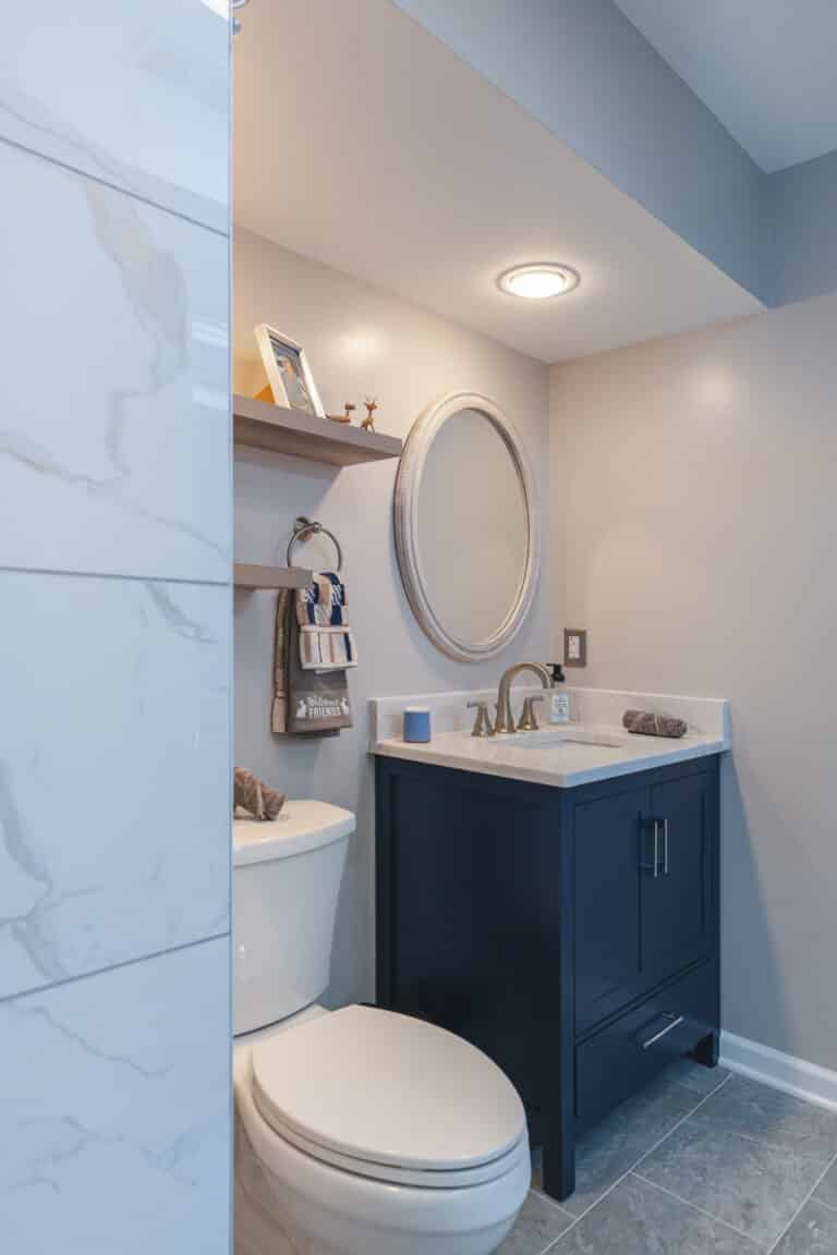 Modern bathroom style with navy vanity, toilet, and shower