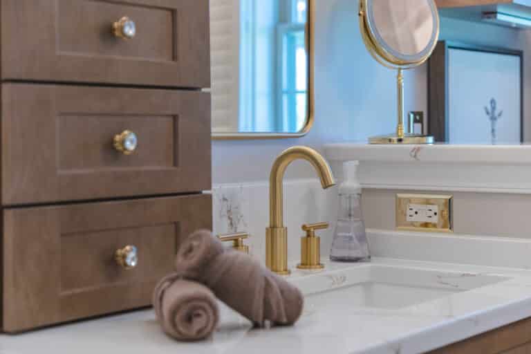 White countertop, brown cabinet, gold faucet.