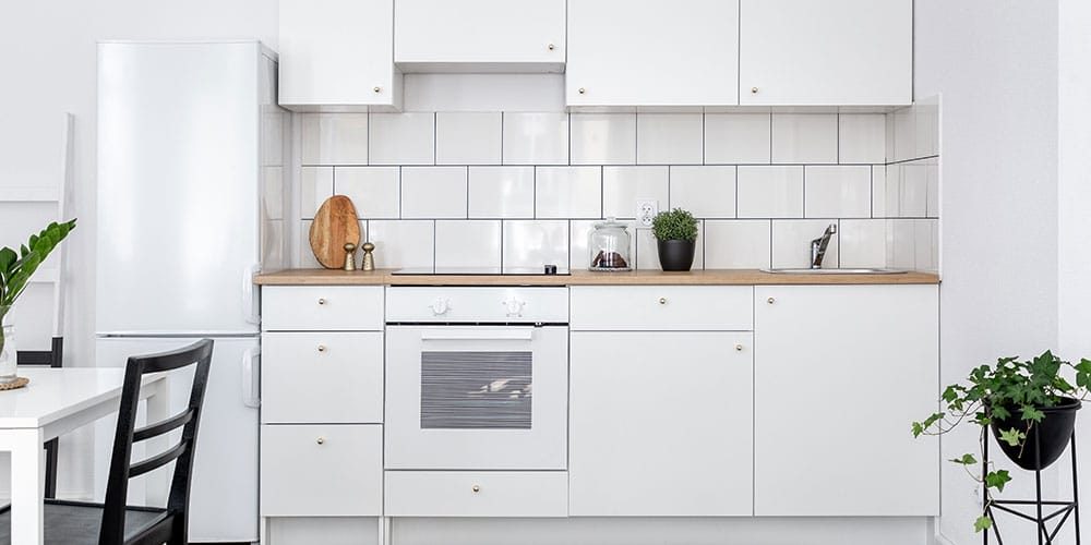 Elegant white kitchen remodeling budget with wood countertop and white tiles backsplash